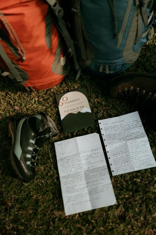 Backpacks, boots, and written plans laid out on grass